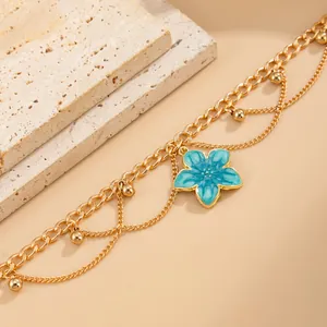 Detailed macro shot of a blue flower enamel anklet with layered gold chains
