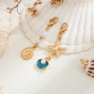 Détail des pendentifs marins : étoile de mer dorée et coquillage bleu avec perles.