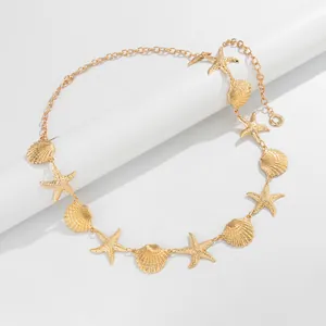 Detailopname van een gouden Boheemse tailleketting met zeesterren en schelpenhangers