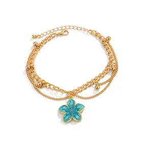 Detailed view of teal enamel flower pendant on layered gold-tone anklet chain