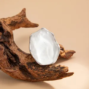 Dettaglio ravvicinato di un anello geometrico argentato con trama a onde d'acqua