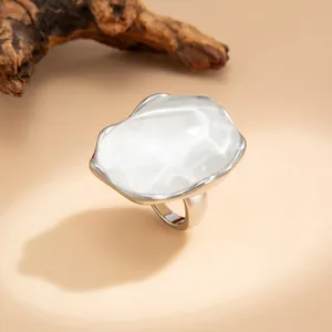 Primo piano di un anello ondulato d'argento irregolare con un centro bianco strutturato