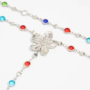 Primer plano detallado de un collar en Y con cristales de colores y flor de plata