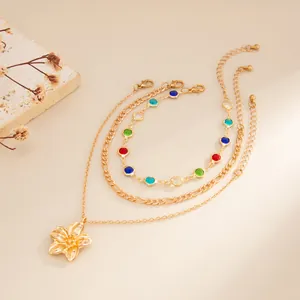 Detail of gold-layered anklets featuring a flower pendant and multi-color stones.