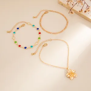 Set of three gold anklets with colorful beads and a flower pendant for beach vacations