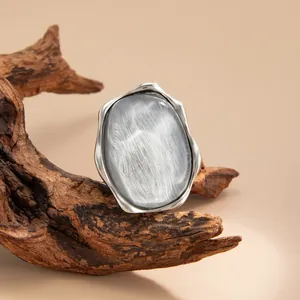 Vista dettagliata di un anello artistico in argento con effetto acqua e pietra grigia.