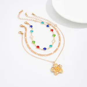 Close-up of a three-layer beach anklet set featuring colorful stones and a gold flower