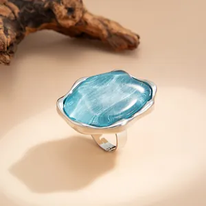 Primo piano di un anello d'argento con una grande pietra blu con effetto onda.