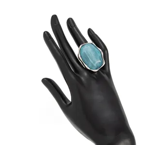 Vista dettagliata di un anello ondulato d'argento con pietra blu su un modello di mano nera