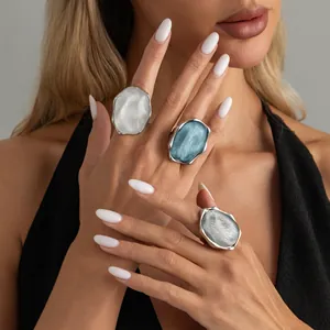 Dettaglio di tre anelli grossi irregolari color argento con trama ondulata e resina.