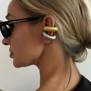 Detailed view of gold and silver threaded C-shape ear cuffs on a model wearing sunglasses