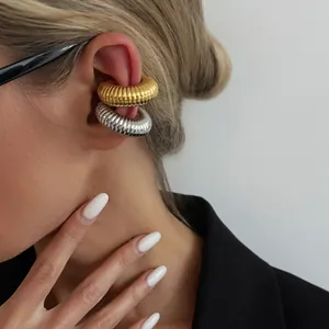Macro detail showing gold and silver textured C-shaped ear cuffs on a model's ear