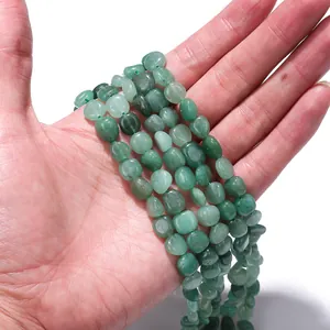 Detail view of natural green stone loose beads held in hand for DIY jewelry making.