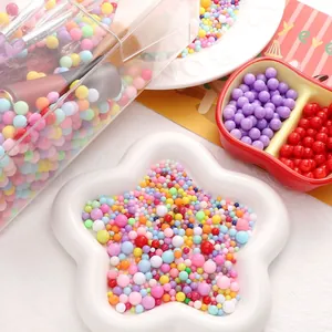 Gros plan de perles rondes en acrylique colorées de tailles mixtes dans un plat en étoile