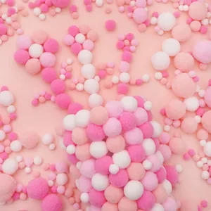 Close-up of soft pink and white polyester pompoms for DIY handmade crafts