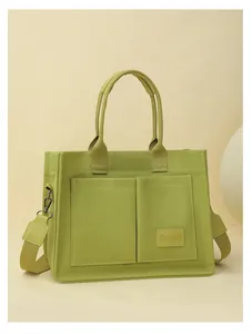 Grand sac fourre-tout en toile verte avec poches avant et large bandoulière.