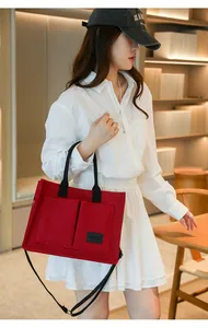 Vue de profil d'un mannequin portant un sac cabas en toile rouge avec poignees noires