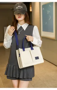 Femme portant un grand sac cabas en toile blanc cassé avec plusieurs poches et bandoulière bleue