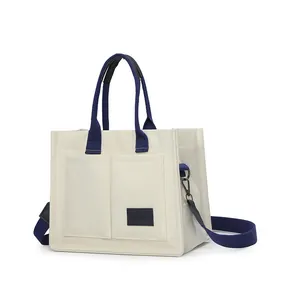 Gros plan sur la toile résistante et les deux poches avant de ce sac fourre-tout blanc