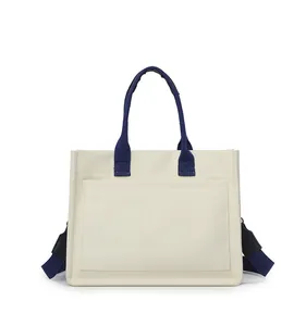 Vue détaillée de face d'un grand sac cabas en toile crème avec de larges bretelles bleues.