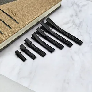 Close-up of seven different sizes of professional matte black metal duckbill hair clips