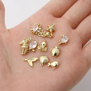 Dettaglio di ciondoli marini in oro 14K con zirconi su una mano per mostrare le dimensioni.