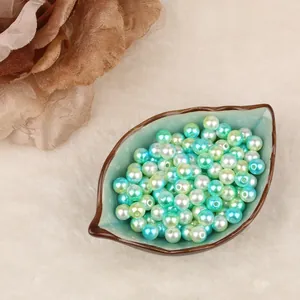 Vista detallada de perlas de imitación redondas de ABS en un plato cerámico de hoja.