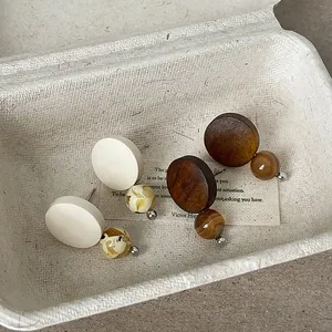 Close-up detail of retro wooden stud earrings with natural stone beads in a paper tray