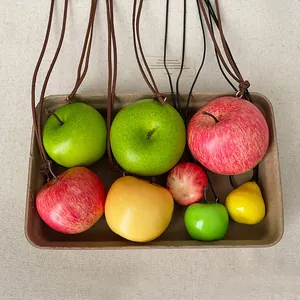 Vista detallada de varios colgantes de manzana realistas con cordones de cuero en bandeja