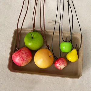 Primer plano de varios colgantes de manzana y pera realistas en una bandeja de papel kraft
