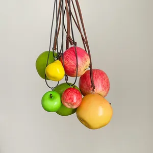 Detalle que muestra varios colgantes de frutas realistas como manzanas y peras