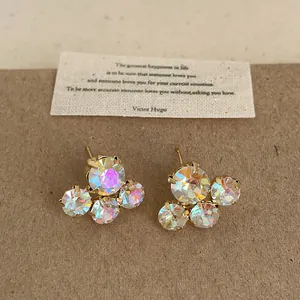 Detailed view of iridescent AB crystal flower stud earrings on a minimalist craft background.