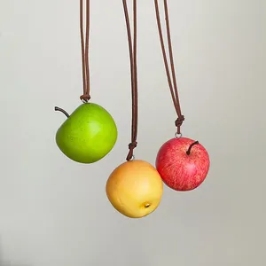 Colgantes de manzana simulados realistas en tres colores con cordones de cuero marrón.