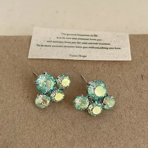 Macro detail of iridescent green crystal flower earrings with a vintage quote card
