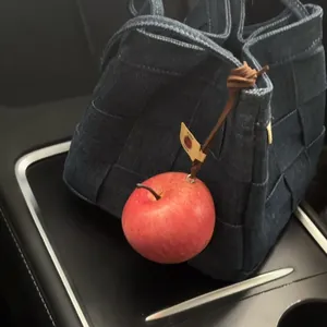 Detalle de un colgante de manzana roja realista colgado de un bolso de tela vaquera azul