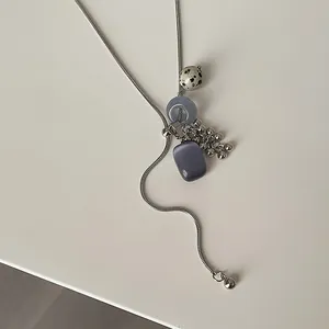 Close-up of spotted stone and grape cluster charms on a silver snake chain necklace