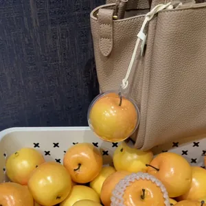 Vista detallada de un colgante de manzana amarilla realista en un bolso de cuero rugoso