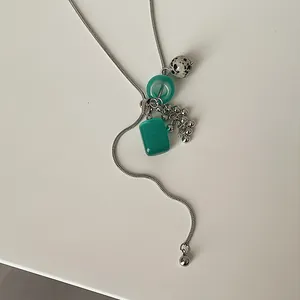 Macro view of silver snake chain lariat necklace with dalmatian stone and green resin charms