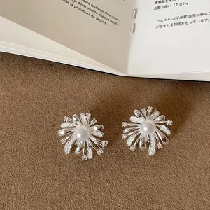 Detailed close-up of silver-toned firework stud earrings with center pearl and zircon