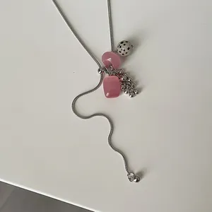 Detailed shot of dalmatian stone and pink bead charms on a silver snake chain necklace