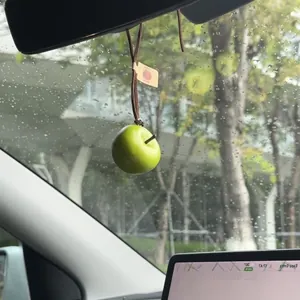 Primer plano de un colgante de coche con forma de manzana verde realista y creativa.