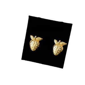 Eleganti orecchini a lobo a forma di fragola dorata su un espositore per gioielli nero