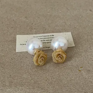 Élégantes boucles d'oreilles avec rose en résille et perle sur un fond neutre texturé.