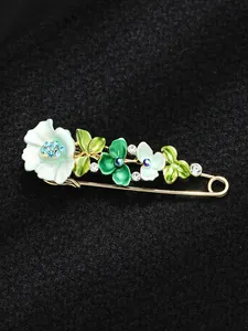 Dettaglio macro di un'elegante spilla a tulipano in smalto verde con strass blu scintillanti