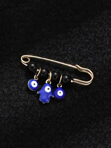 Detailed macro view of ethnic style blue evil eye brooch with gold pin and black beads