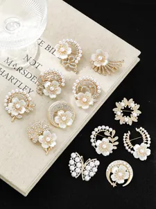 Nahaufnahme verschiedener eleganter Perlen- und Strass-Blumenbroschen in diversen Designs