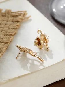 Detail der Seitenansicht einer goldenen Ginkgoblatt-Brosche im Vintage-Stil auf Buchseite
