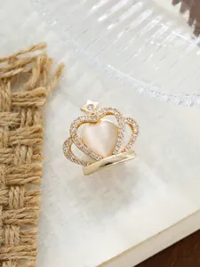 Detailansicht einer goldenen Kronenbrosche im Vintage-Stil mit Herzstein und Kristallakzenten