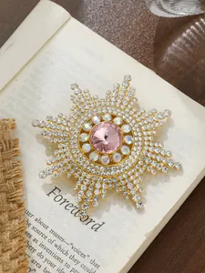 Nahaufnahme einer Sonnenblumen-Brosche mit großem rosa Edelstein und Strass