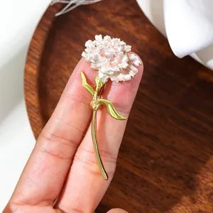 Detailed macro view of an elegant pink carnation flower brooch with gold and green stem.